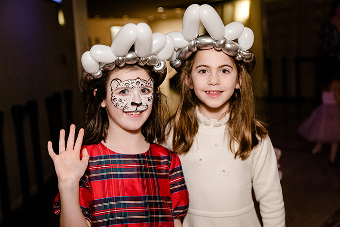 Young guests showing off their holiday face paint and balloon art